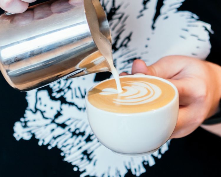 person pouring milk into coffee on a latte art workshop in london