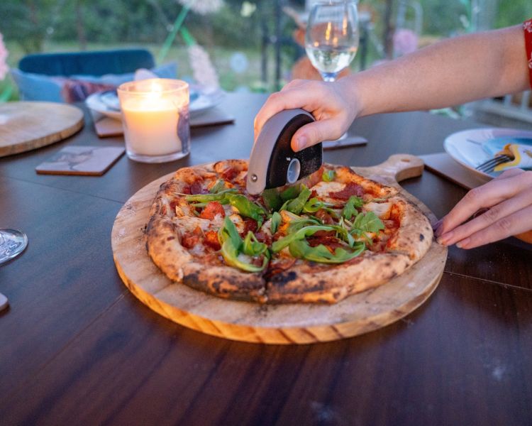 A lady cutting a hand made pizza