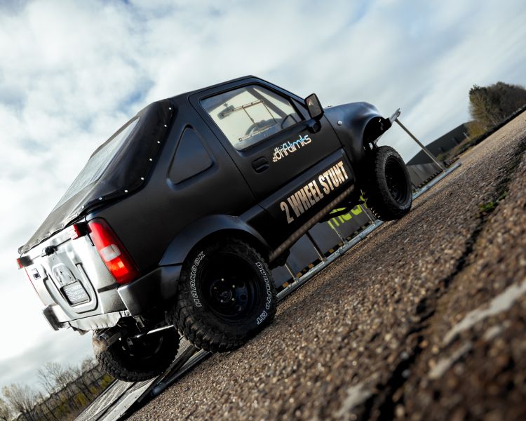 back view of stunt car being driven up a ramp on two wheels on a stunt driving experience