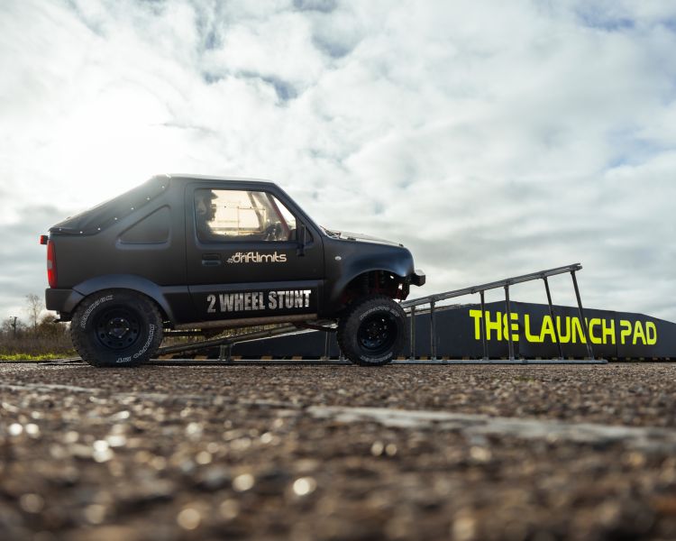 stunt car being driven up a ramp on two wheels on a stunt driving experience