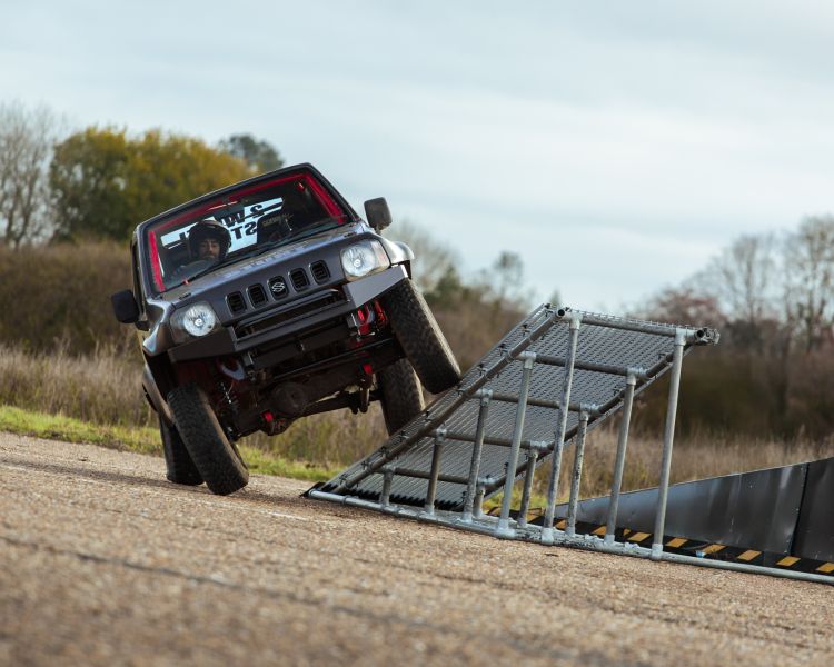 stunt car being driven up a ramp on two wheels on a stunt driving experience