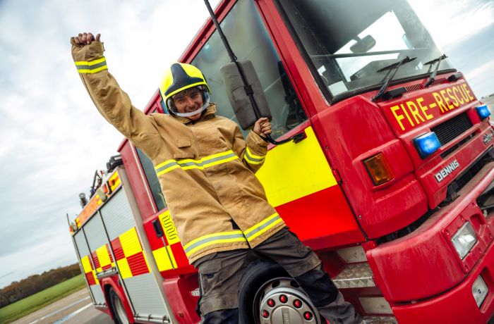 boy dressed as fireman next to fire engine on a fire fighting experience
