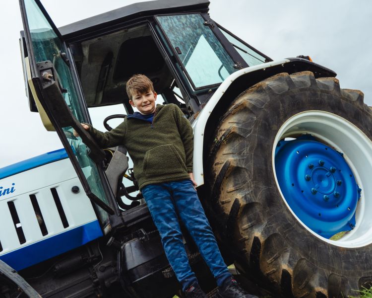 boy hanging to side of a lamborghini tractor on a tractor driving experience