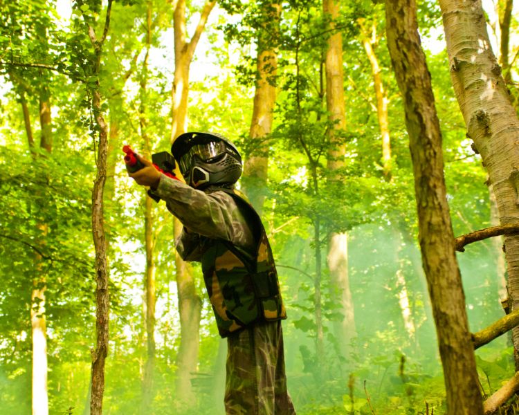 child aiming paintball gun in forest on mini paintball experience