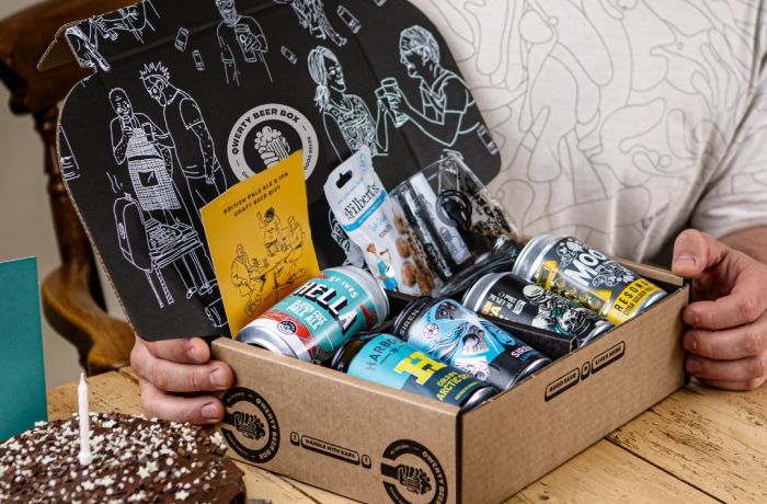 Man opening qwerty gift box of five cans of pale ale with snacks on birthday