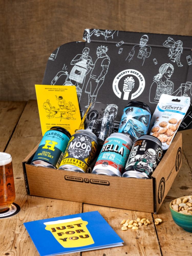 Qwerty gift box of five cans of pale ale and snacks on wooden table