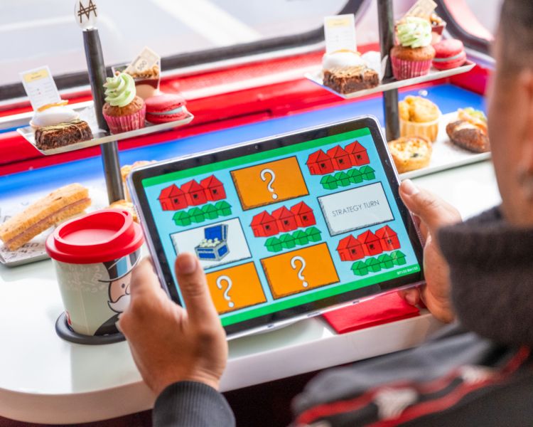 man playing game on tablet on monopoly afternoon tea bus tour