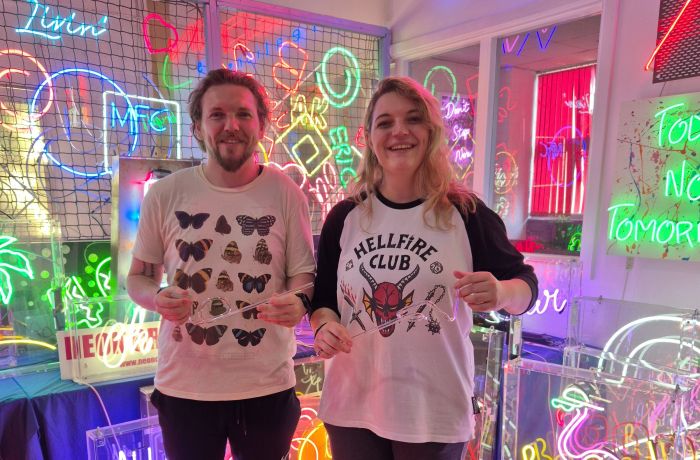 couple with their bent glass on neon sign taster session