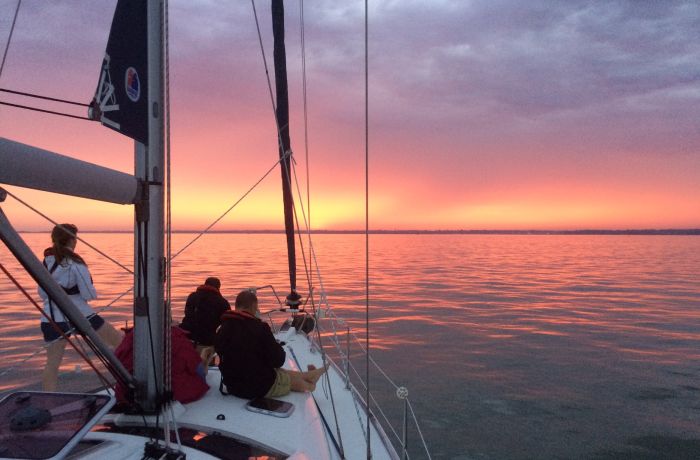 people sitting at front of yacht on the solent at sunset