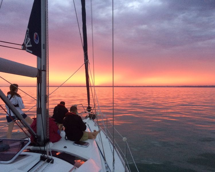 people sitting at front of yacht on the solent at sunset