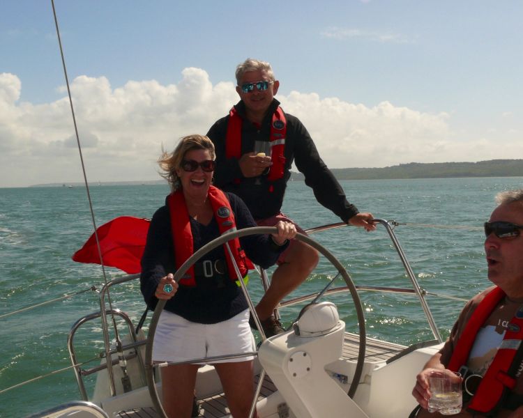 guests on the helm of a yacht sailing on the solent