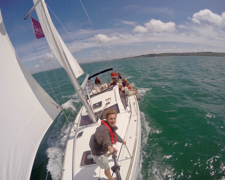 skipper taking photo of yacht with go-pro while sailing on the solent