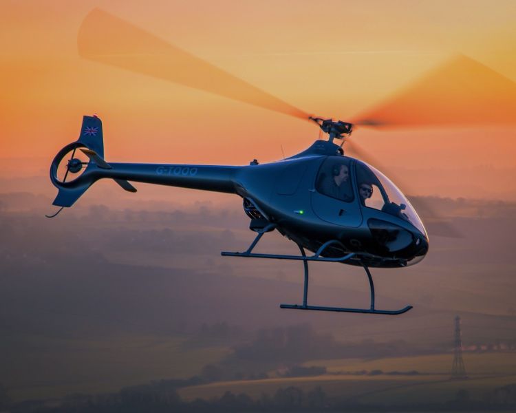 a cabri g2 helicopter with sunset behind it