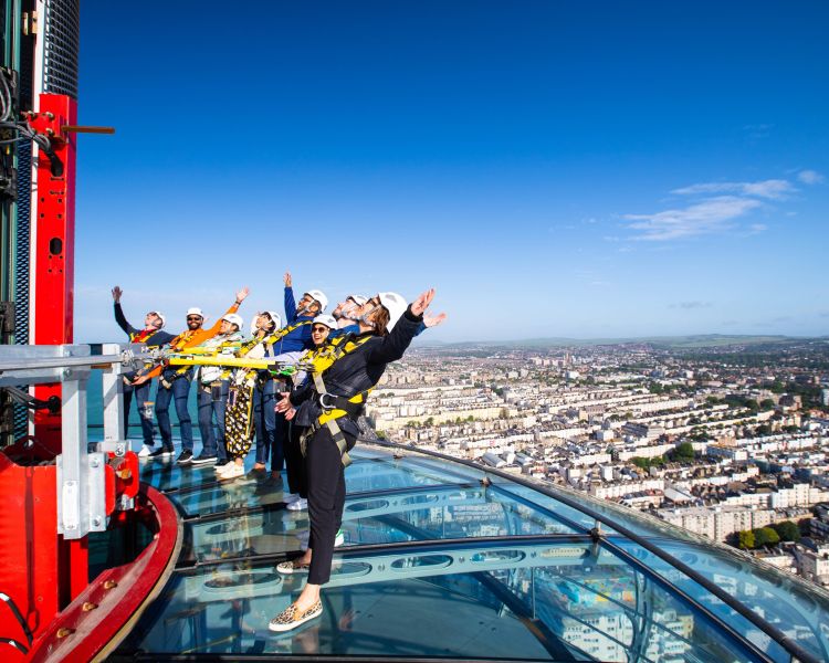 people on the i360 sky walk looking up at the tower