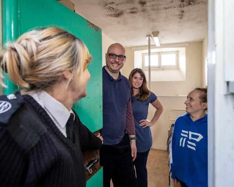 a guard opening the door to a prison cell with people inside on a prison escape room experience day