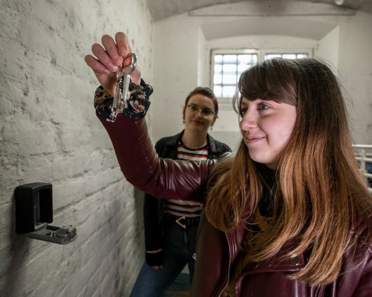 two people in a prison cell, one holding a set of keys as part of a prison escape room experience day