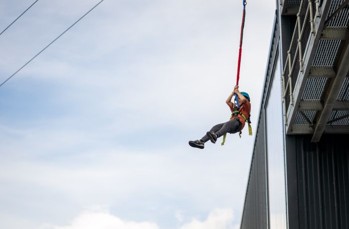 person jumping off the side of a building doing the leap of faith at adventure activity centre in wales