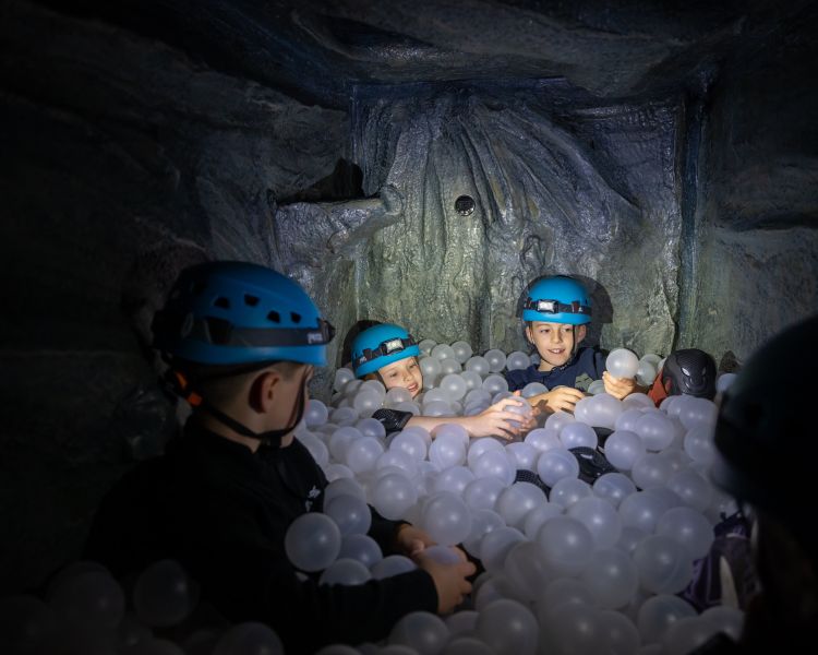 kids playing in ball pit on indoor caving experience at activity centre in wales