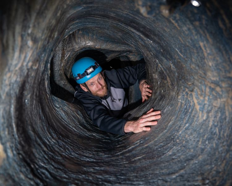 man crawling through tunnel on indoor caving experience at activity centre in wales