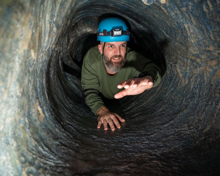 man crawling through tunnel on indoor caving experience at activity centre in wales