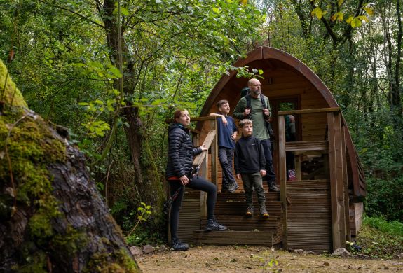 family outside a wooden pod at activity centre in wales on overnight stay