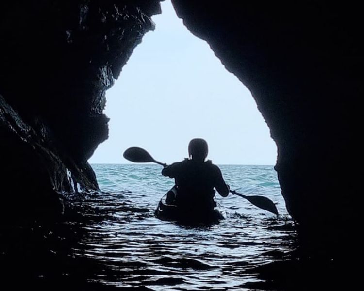 Kayaker going through cave on pembrokeshire coast