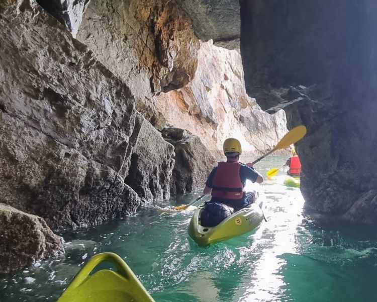Kayakers sailing through sea caves on pembrokeshire coast