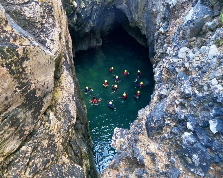 Group in water in sea cave on coasteering experience in pembrokeshire