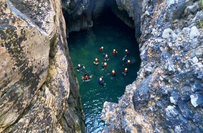 Group in water in sea cave on coasteering experience in pembrokeshire