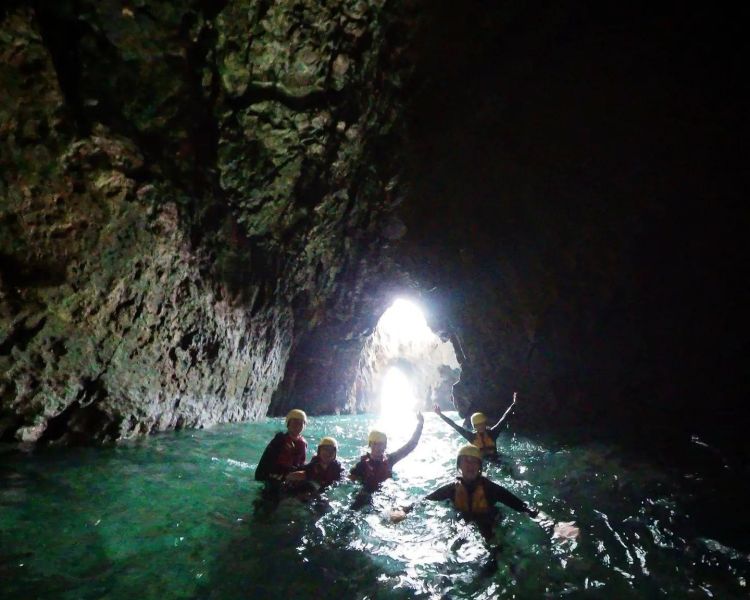 Group swimming in cave on coasteering experience in pembrokeshire