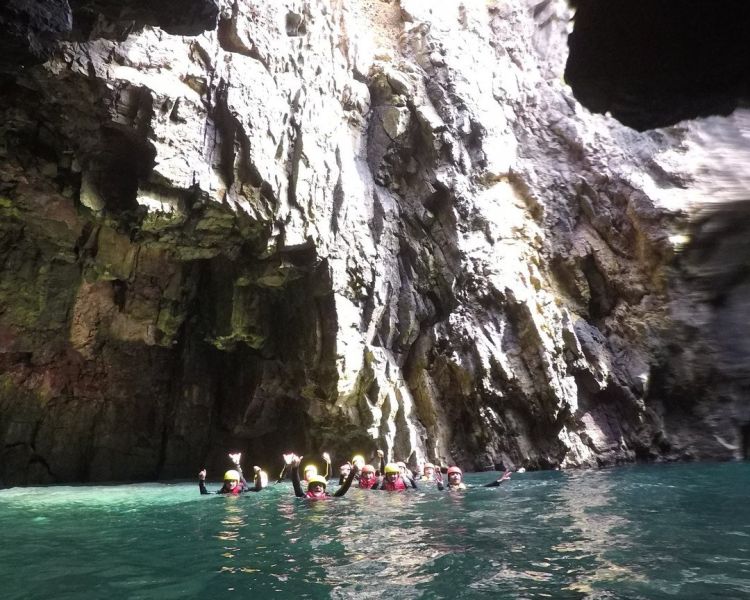People in water in sea cave on coasteering experience in pembrokeshire
