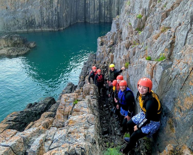 People scrambling along sea edge on coasteering experience in pembrokeshire