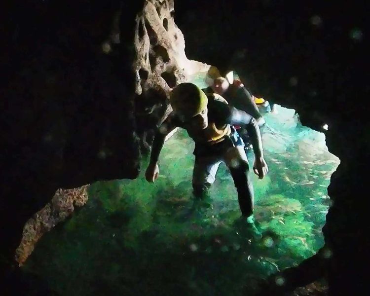 Person crawling into cave on coasteering experience in pembrokeshire
