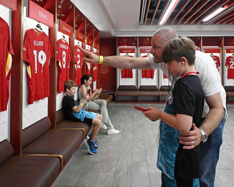 A father and son exploring the dressing room with audio guide