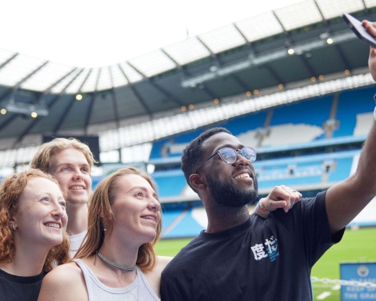 A group of four people taking a selfie in the man city stadium
