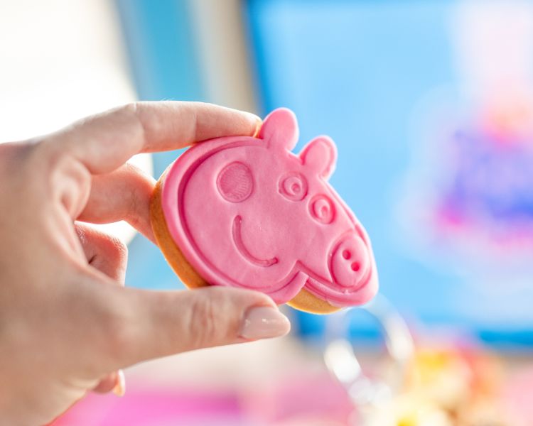 Hand holding a pink peppa pig biscuit