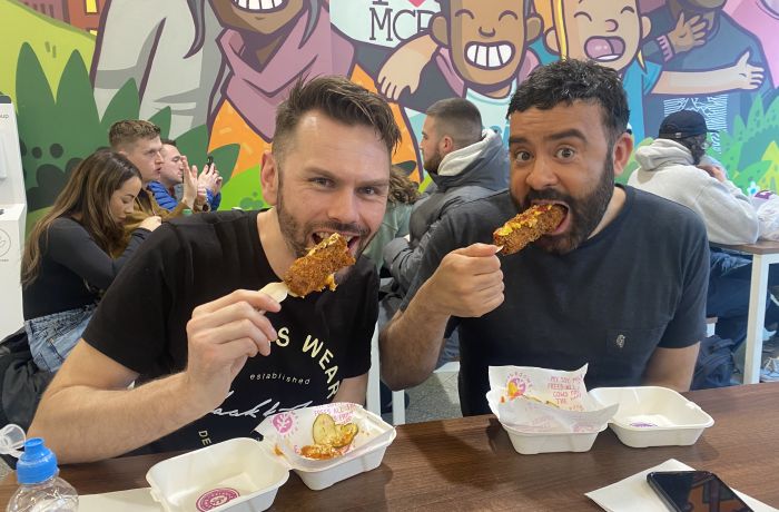 Two men eating corndogs on manchester food tour