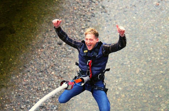 man doing a bungee jump over a river on a bungee jump experience day