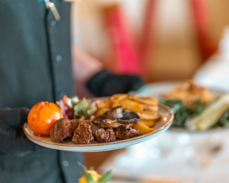 Waiter carrying plates of food at bagden hall restaurant