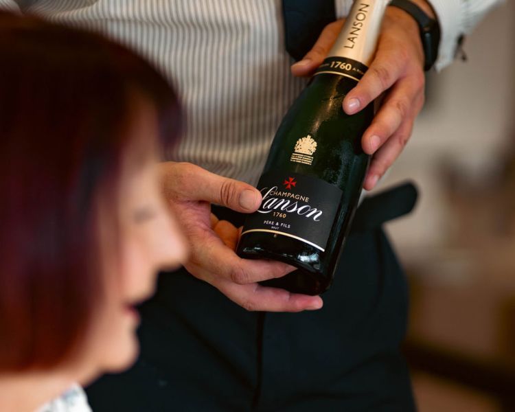Waiter holding bottle of lanson champagne for afternoon tea