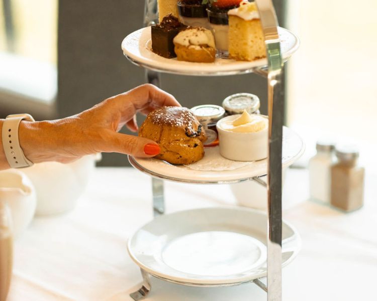 Woman taking scone from afternoon tea at grinkle park