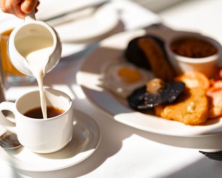 Pouring milk into coffee at breakfast at grinkle park