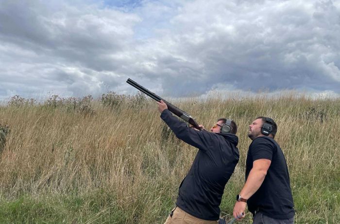 Man clay shooting with instructor