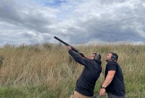 Man clay shooting with instructor