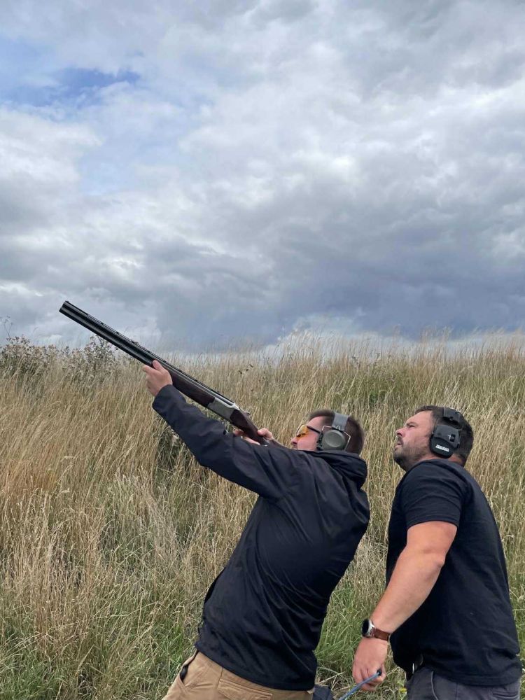 Man clay shooting with instructor