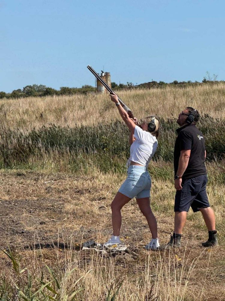 Woman clay shooting with instructor