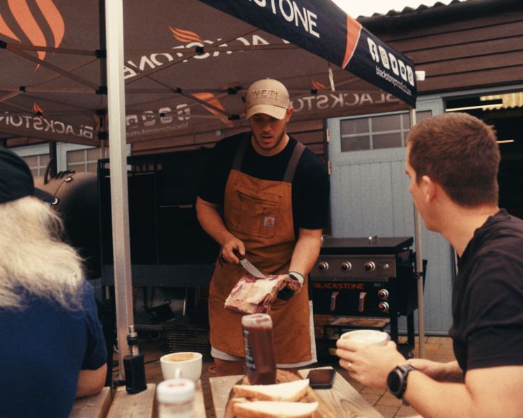 Cook showing students piece of meat for blackstone griddle bbq experience