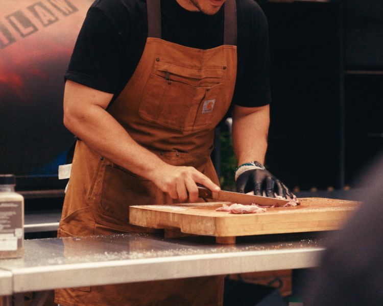 Cook preparing meat fo blackstone griddle bbq cooking demonstration
