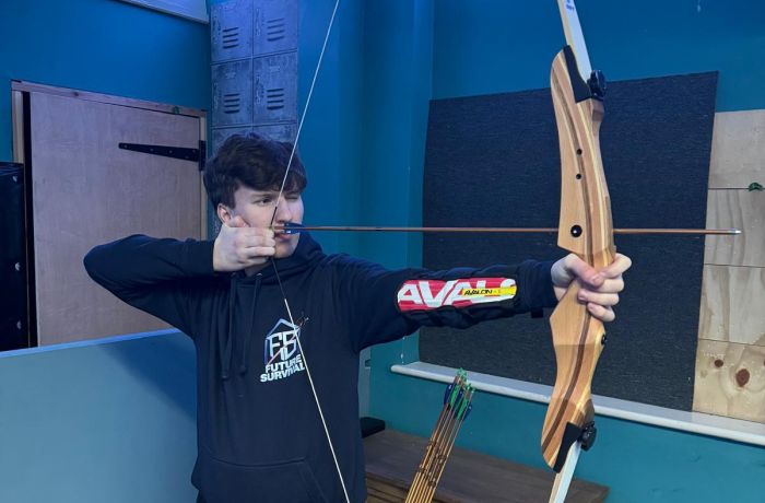 An instructor aiming a bow indoor archery