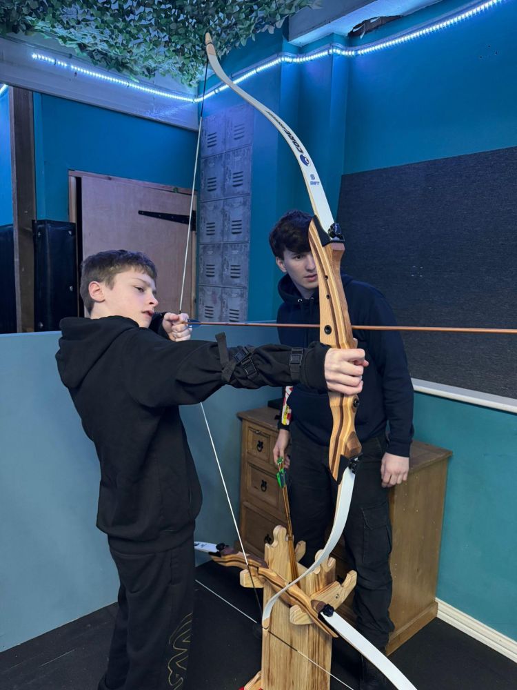 An instructor and young boy indoor archery